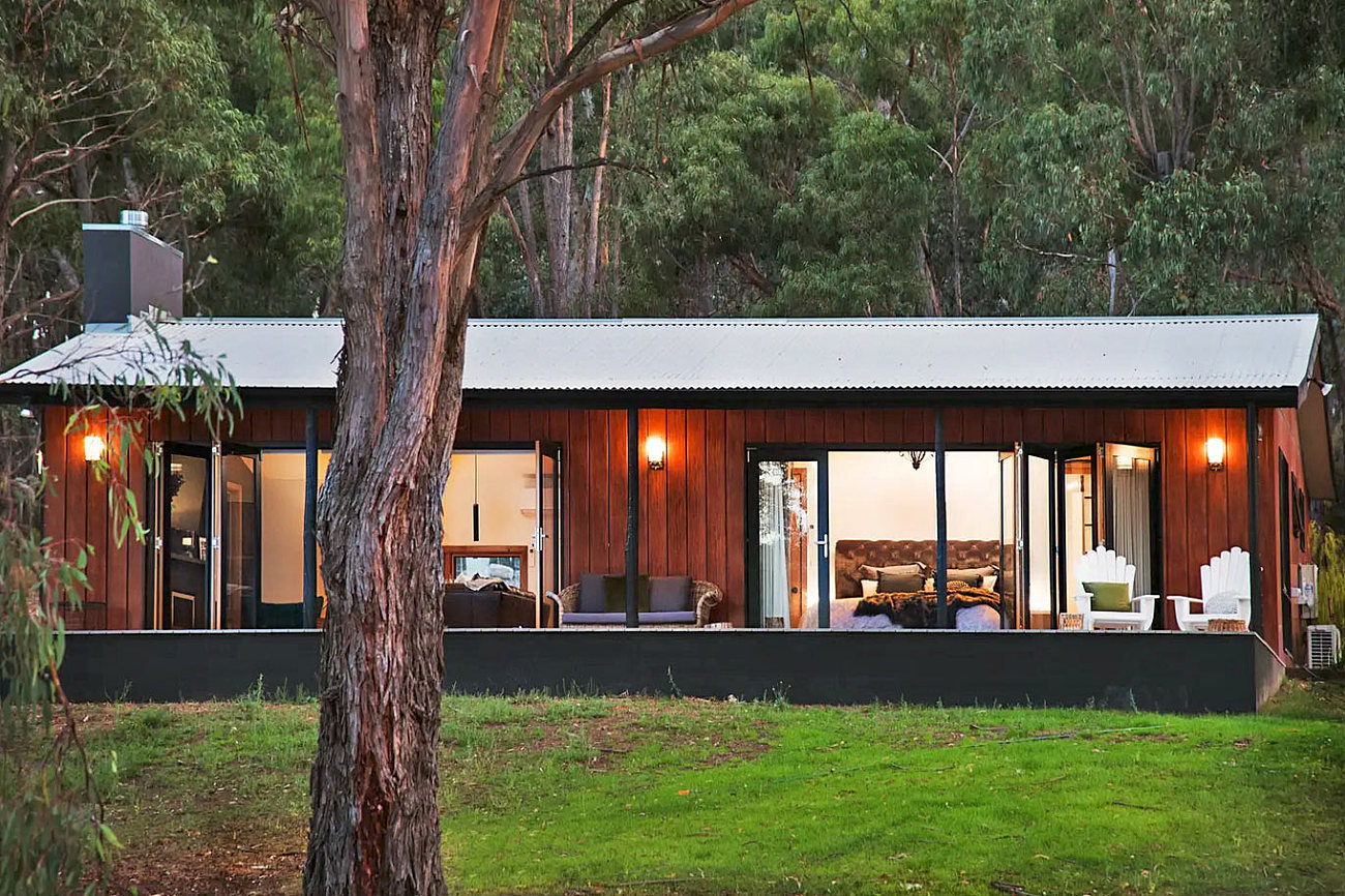 Kurrajong Retreat's timber villa lit up at dusk among the gums